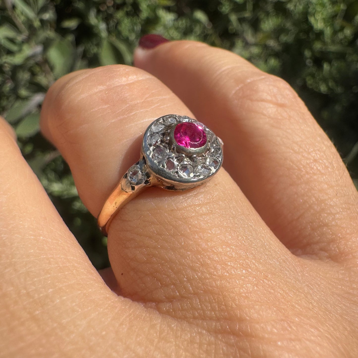 18K gold ring set with a round Ruby at the center, surrounded by a halo of old-cut Diamonds.