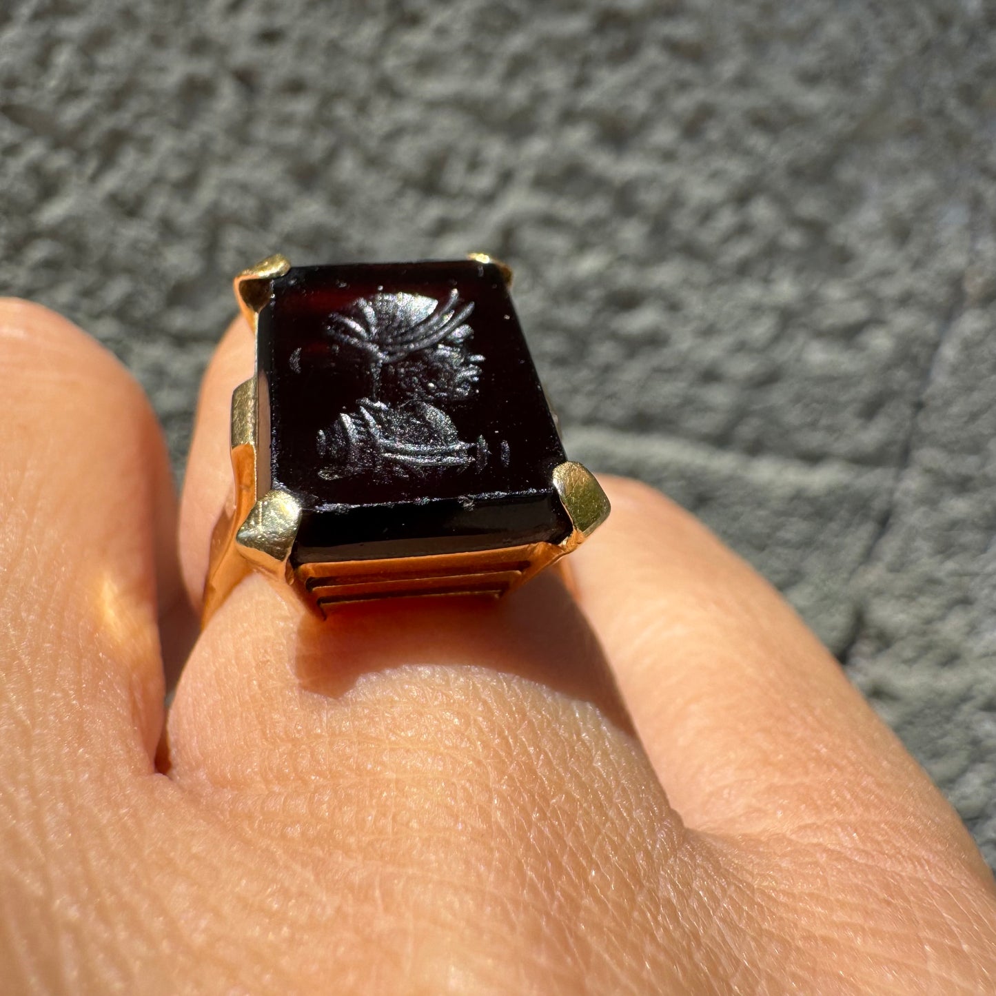 18K gold ring set with a carved dark stone featuring a classical warrior profile.