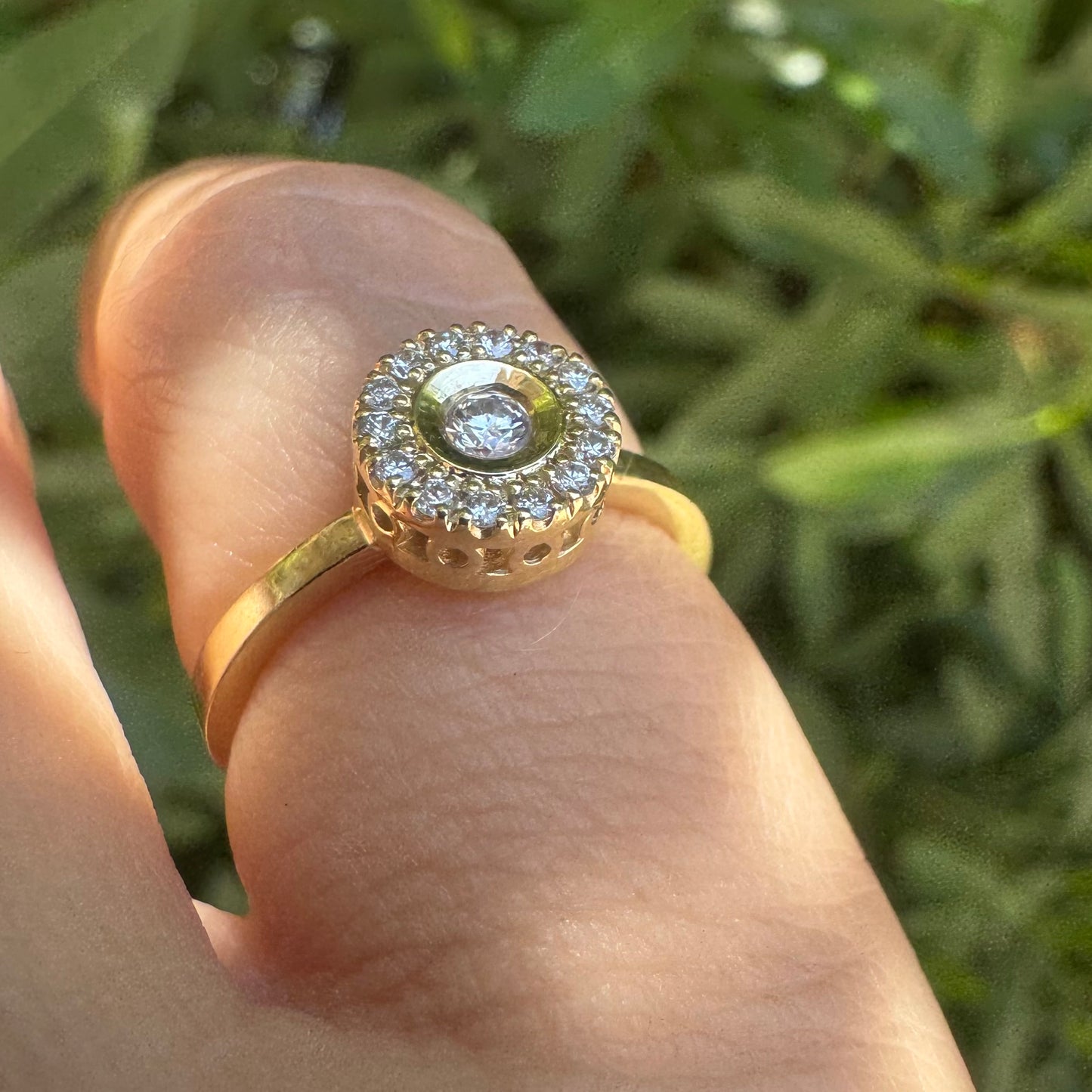 14K gold ring set with a bezel-set central Diamond, surrounded by a sparkling halo of brilliant-cut Diamonds.
