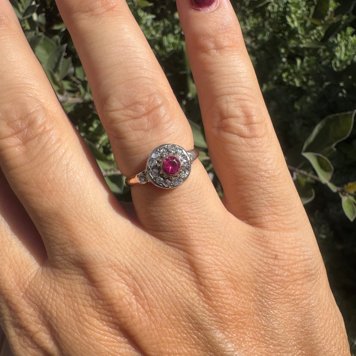 18K gold ring set with a round Ruby at the center, surrounded by a halo of old-cut Diamonds.