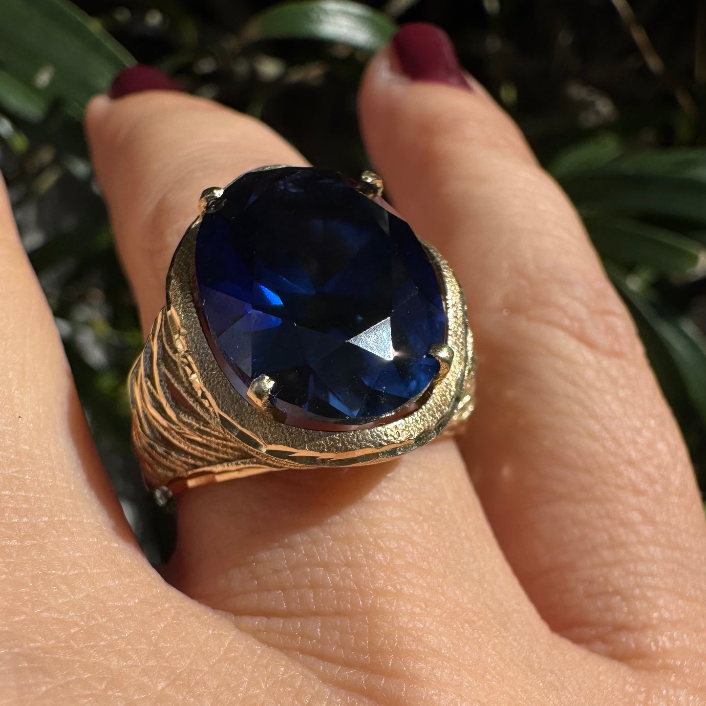 14K gold ring set with a deep navy-blue oval Sapphire in a dramatic openwork setting