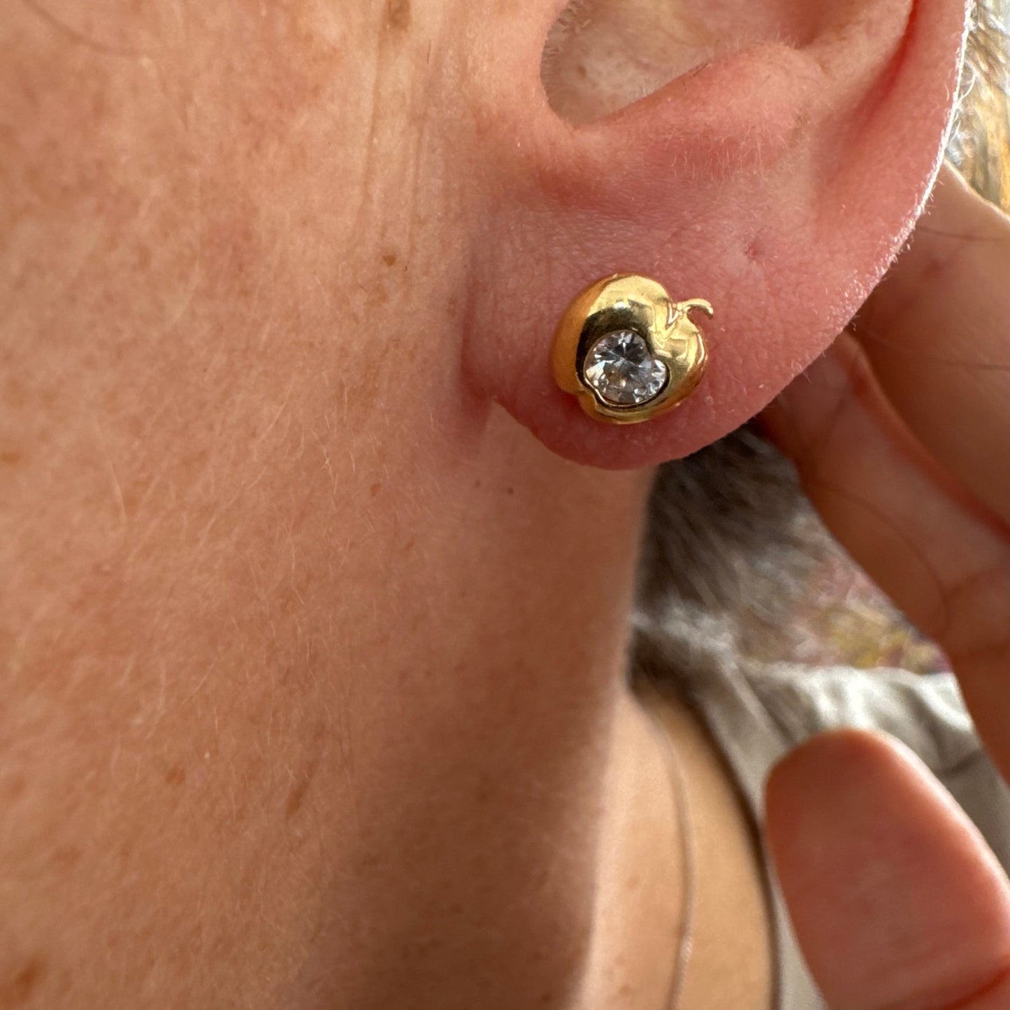 עגילי זהב 14 קראט צמודים לאוזן בצורת תפוח, בעיצוב פיסולי ורך עם אבן שקופה משובצת במרכז.