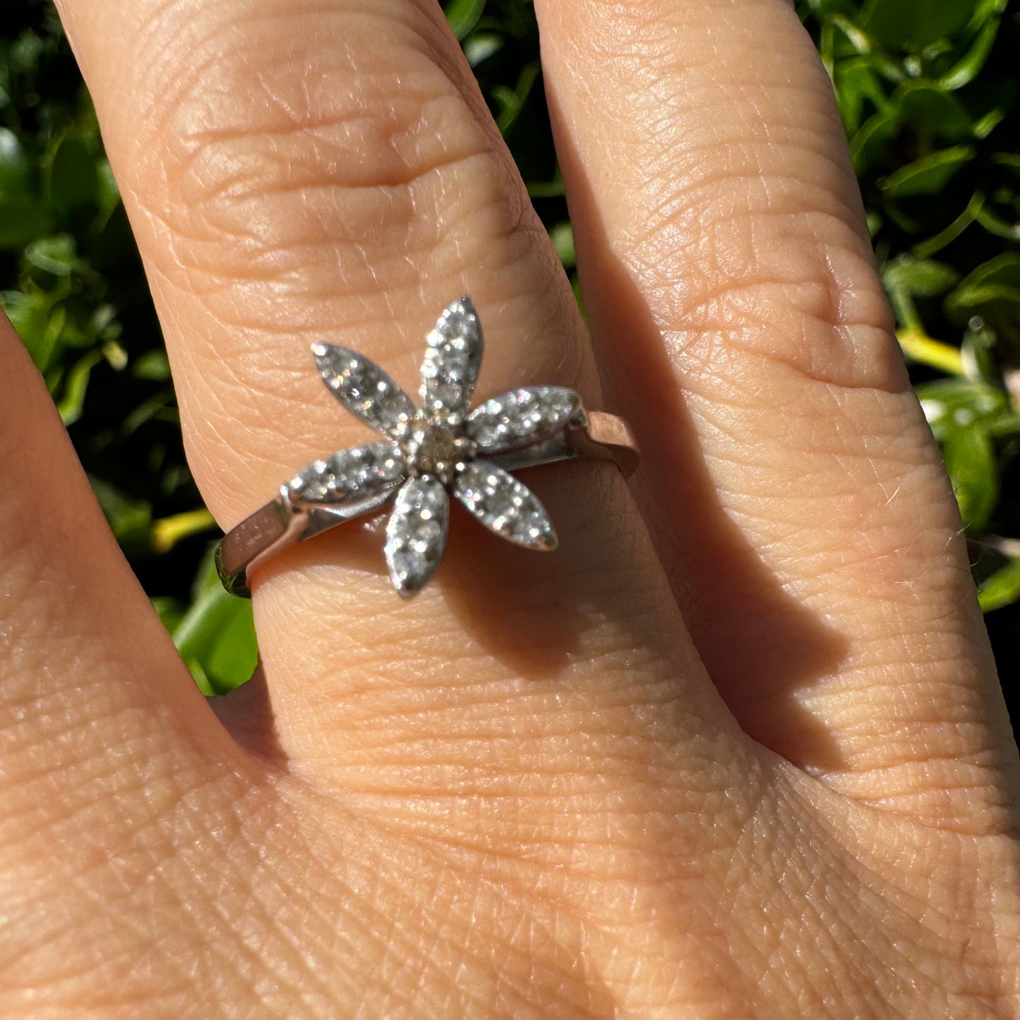 טבעת זהב לבן 14 קראט בעיצוב פרח בעל שישה עלי כותרת, שכל אחד מהם משובץ ביהלומים קטנים ומנצנצים.