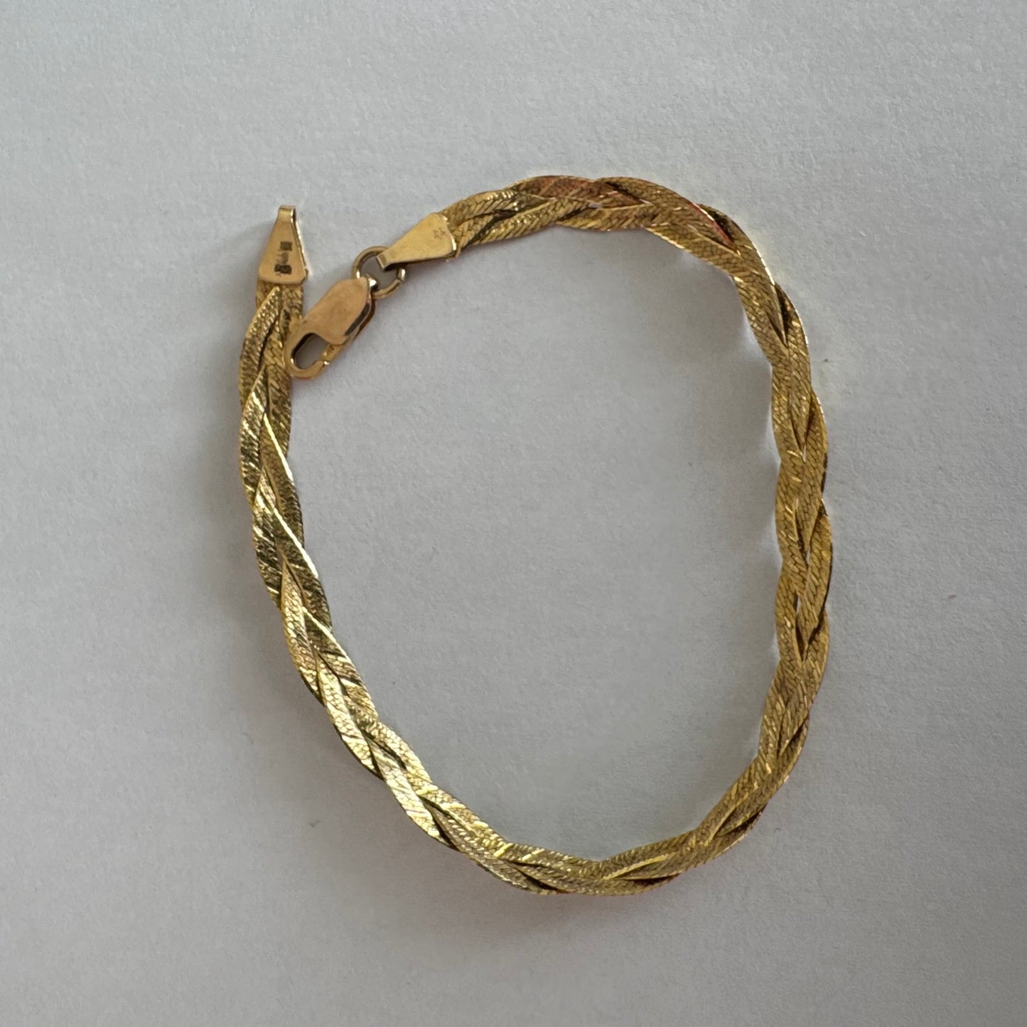 צמיד זהב צהוב 10 קראט בעיצוב קלוע עם טקסטורה עדינה שמחזירה אור וברק רך.