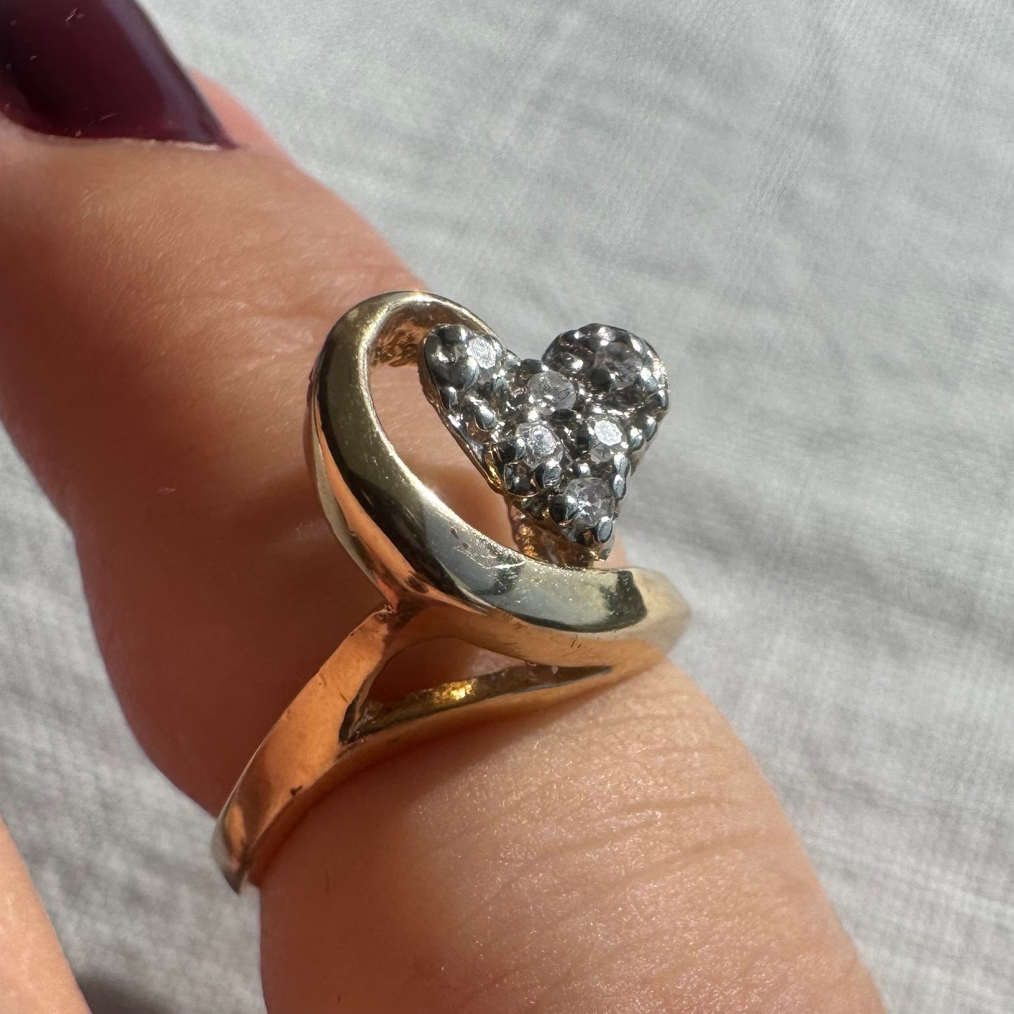 14K gold ring featuring a Diamond-studded heart embraced by a flowing golden curve.