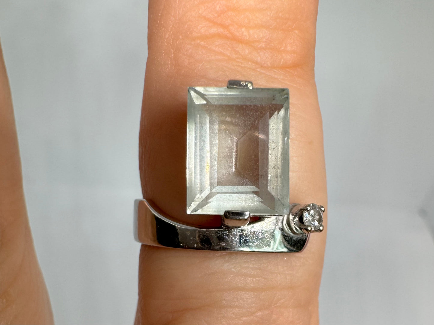 18K gold ring set with a rectangular step-cut Aquamarine set in a sculptural white gold band & a sparkling Diamond