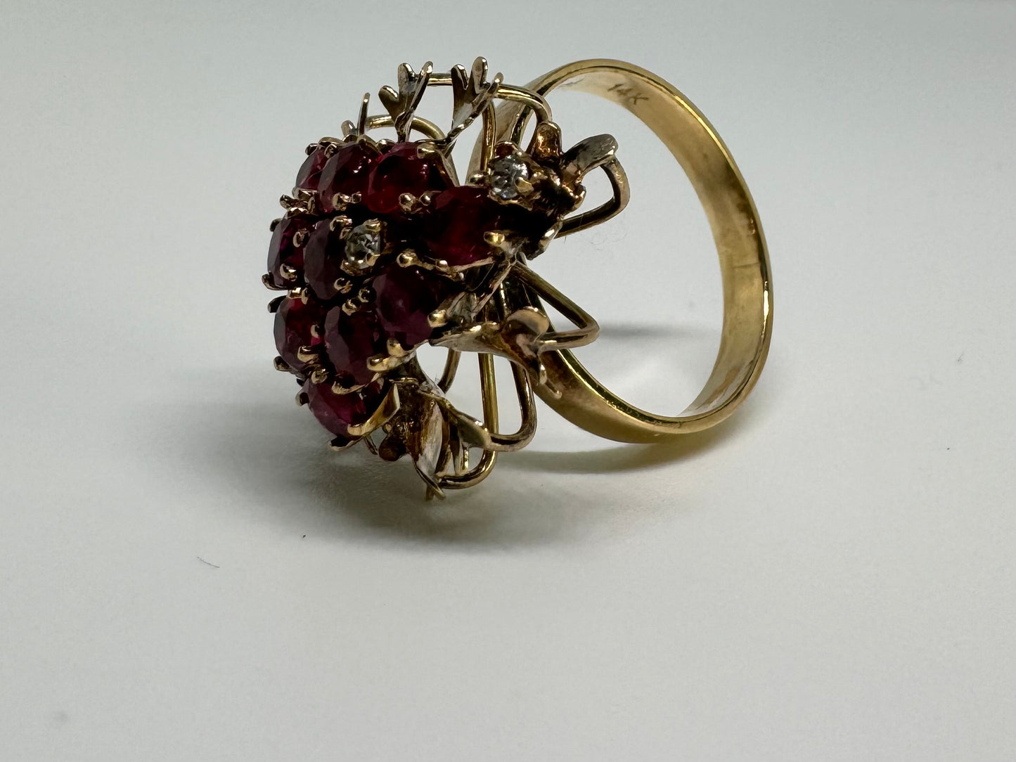 14K gold ring set with a vibrant cluster of deep red rubies and sparkling diamonds.