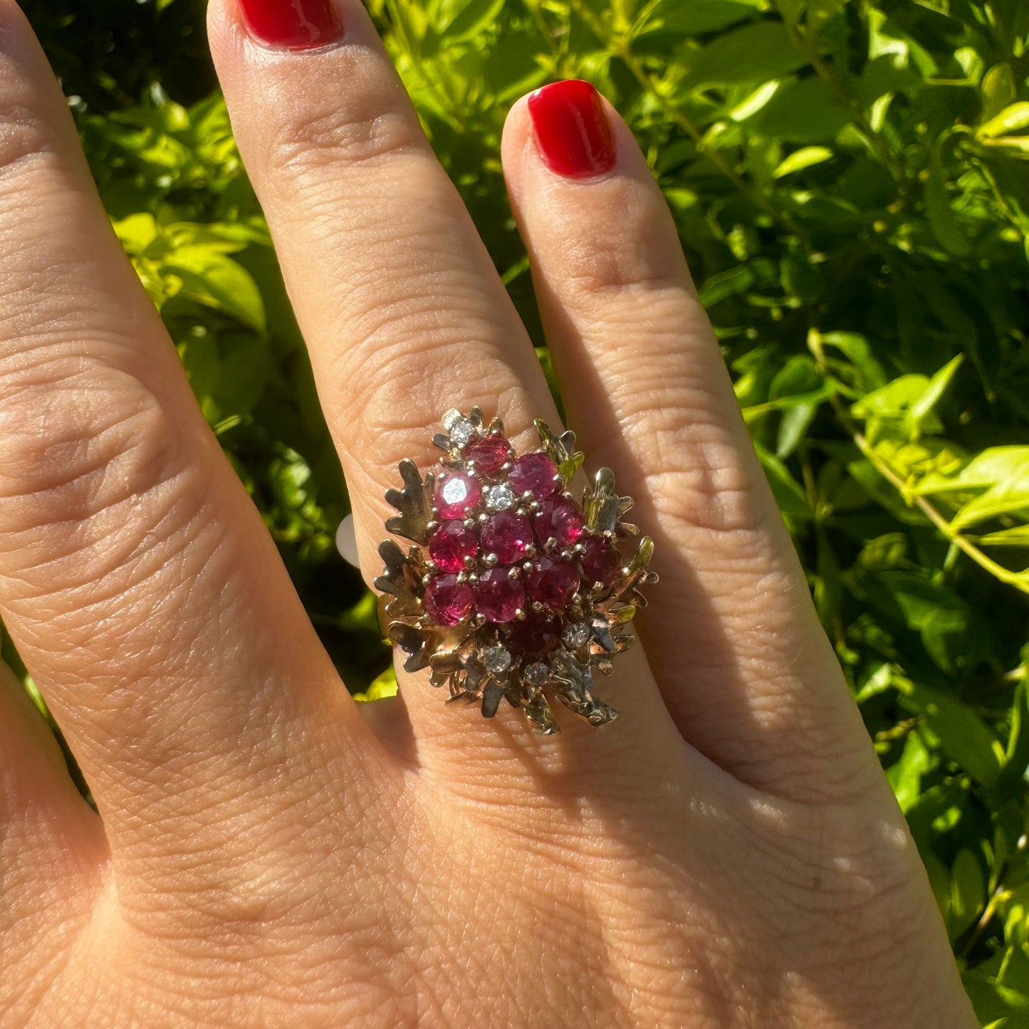14K gold ring set with a vibrant cluster of deep red rubies and sparkling diamonds.