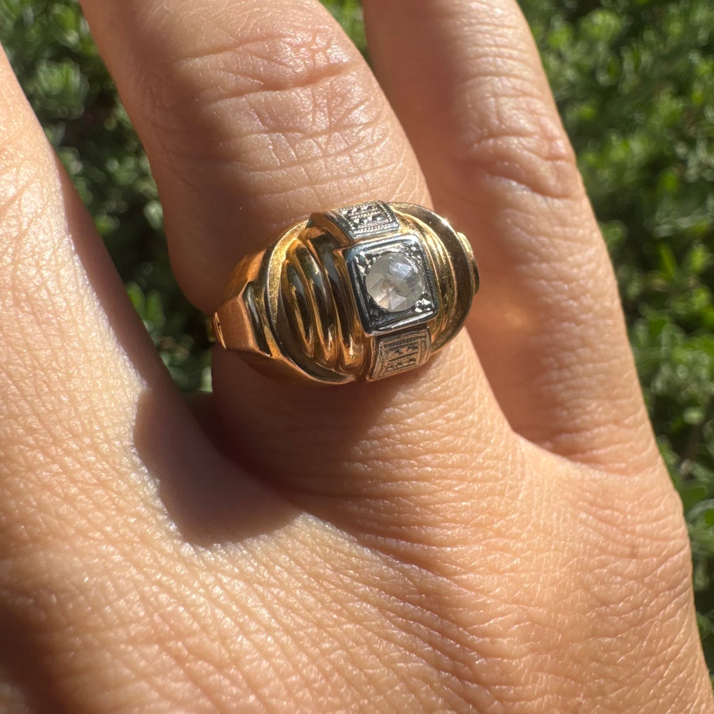 18K gold ring featuring a central round Diamond set in a square bezel with decorative details.