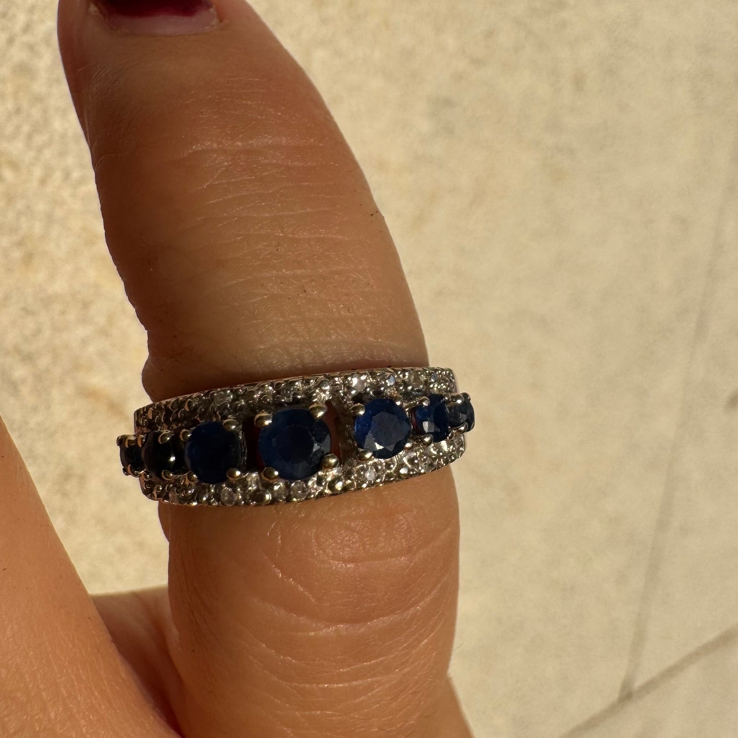 18K gold ring set with deep blue sapphires in a classic round cut, framed by two shimmering rows of brilliant Diamonds.