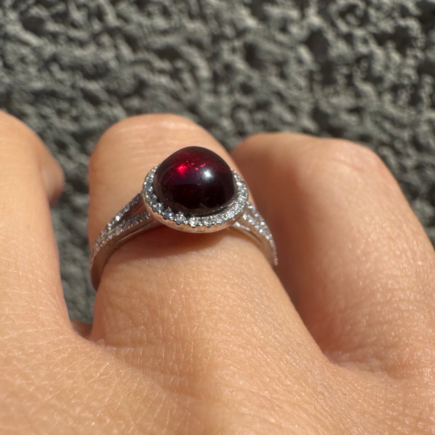 14K gold ring set with a deep red cabochon Garnet, surrounded by a halo of sparkling Diamonds