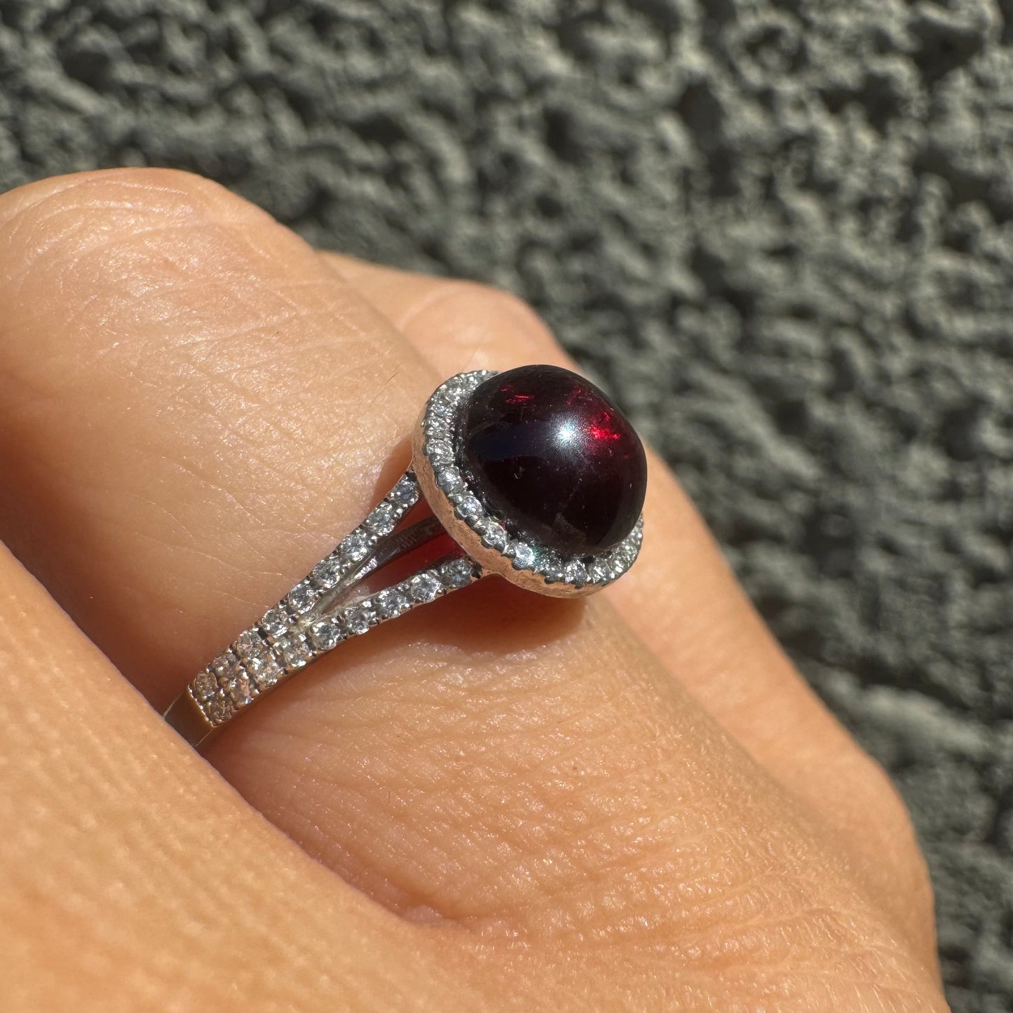 14K gold ring set with a deep red cabochon Garnet, surrounded by a halo of sparkling Diamonds