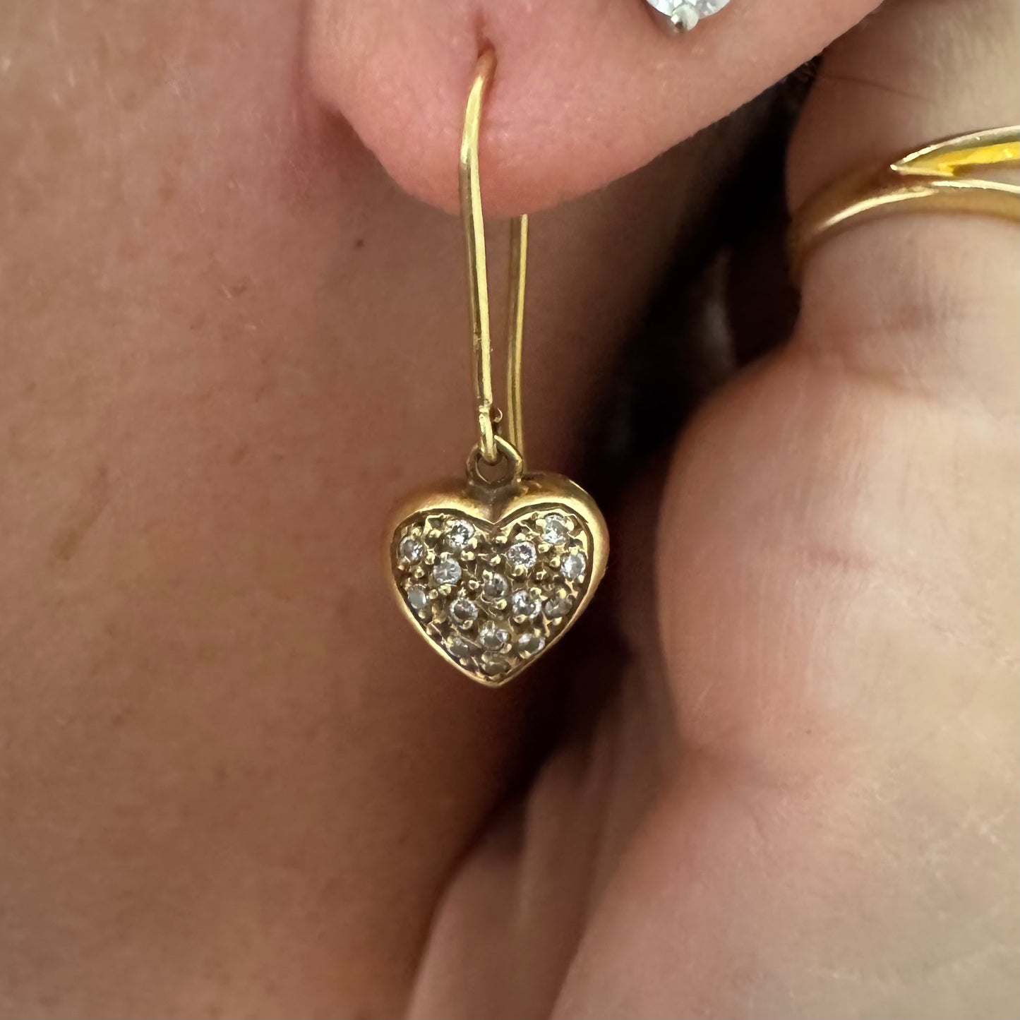עגילי זהב צהוב 18 קראט תלויים בצורת לב, משובצים יהלומים קטנים המוסיפים ברק עדין ונוכחות אלגנטית.