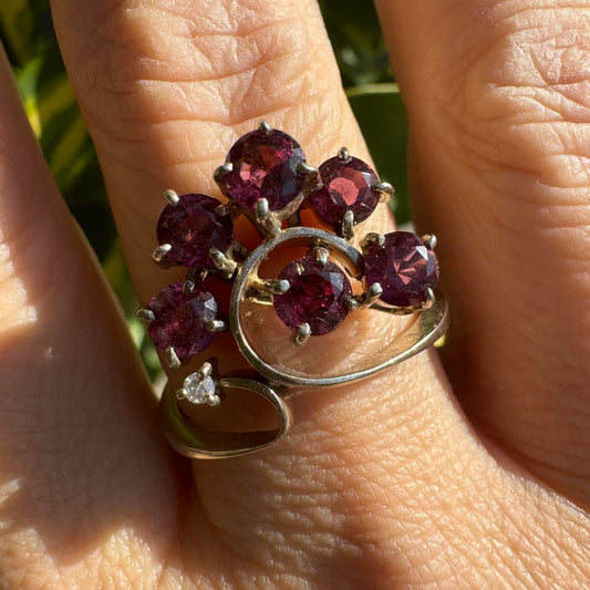 14K gold ring with an open, flowing design, set with multiple pink Tourmaline stones and accented by a Diamond