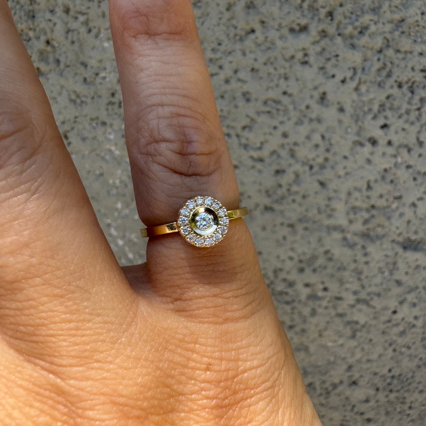14K gold ring set with a bezel-set central Diamond, surrounded by a sparkling halo of brilliant-cut Diamonds.