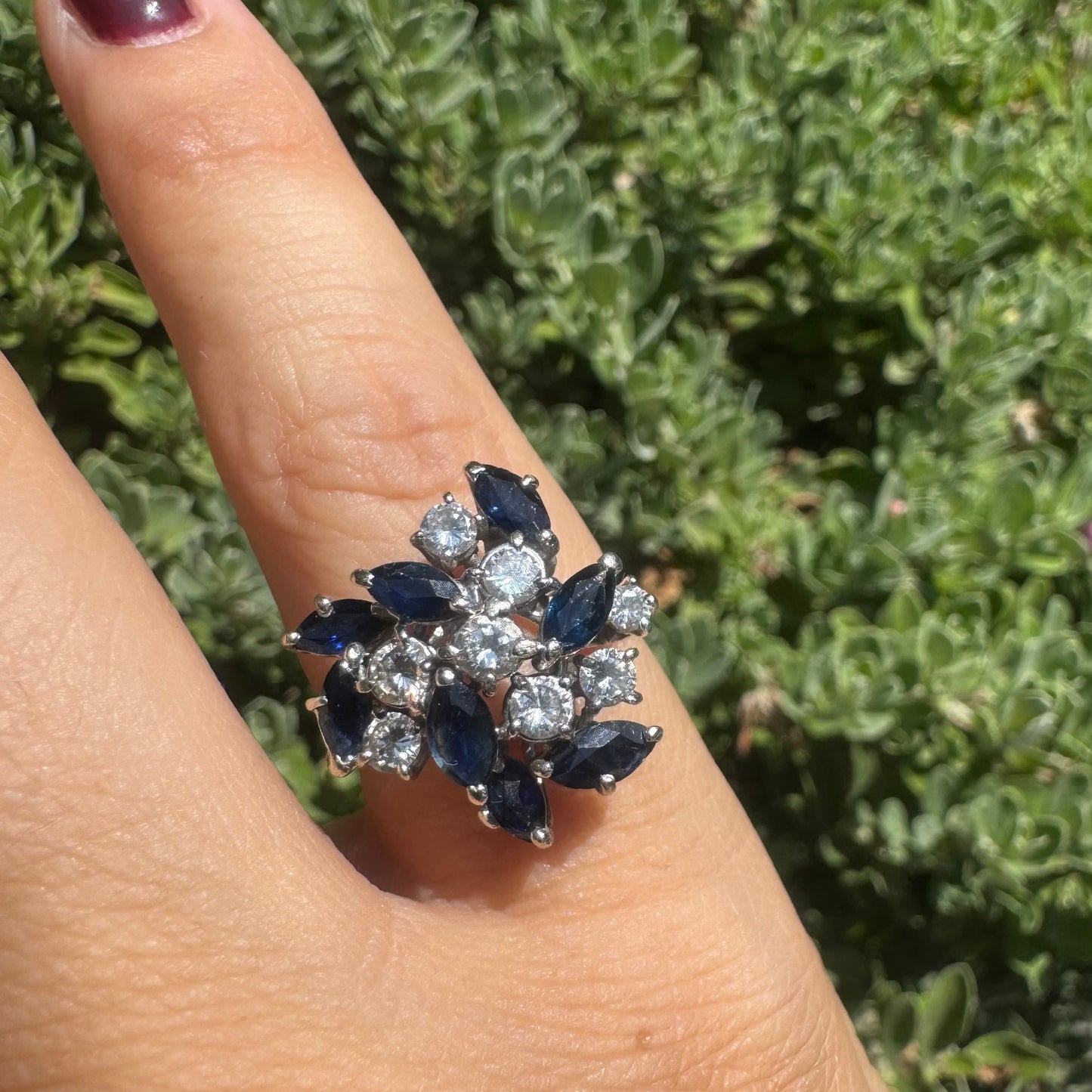 18K gold cluster ring featuring marquise-cut blue sapphires and round brilliant Diamonds arranged in a floral design.
