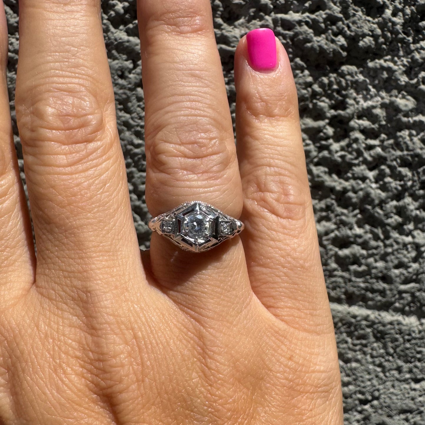 14K gold ring set with a central round diamond, framed by geometric Art Deco details and additional accent stones.