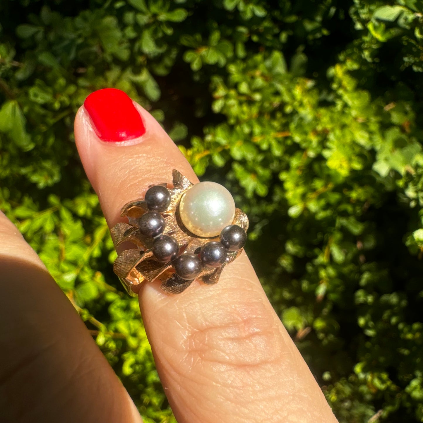 14K gold ring set with a luminous white Pearl at its center surrounded by a delicate circle of black Pearls.