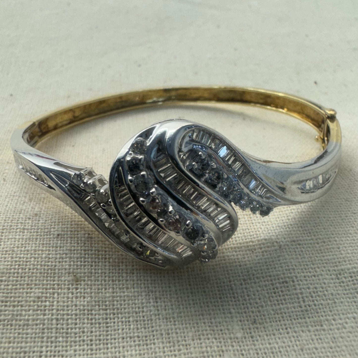 צמיד מרהיב מזהב לבן 14 קראט, בעיצוב גלים דינמי המשובץ בשיבוץ מרוכב של יהלומים עגולים ובחיתוך באגט.