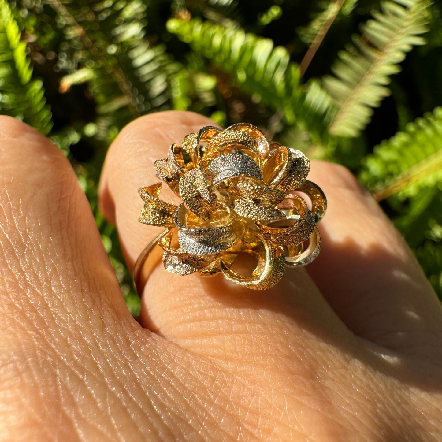 18K gold ring set with intricately textured loops in yellow, white, and rose gold, forming a bold floral-inspired sculptural design.