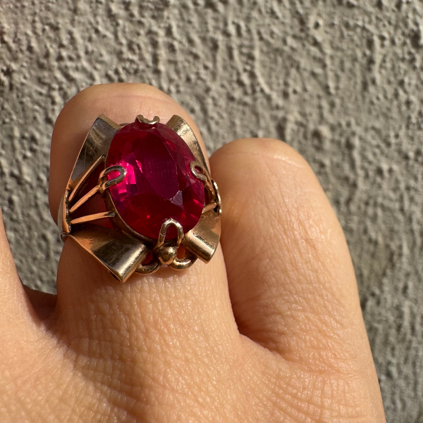 טבעת זהב 14 קראט משובצת אבן אובלית גדולה בצבע אדום חי במסגרת גאומטרית מיוחדת.