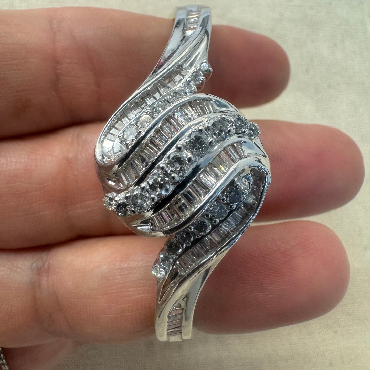 צמיד מרהיב מזהב לבן 14 קראט, בעיצוב גלים דינמי המשובץ בשיבוץ מרוכב של יהלומים עגולים ובחיתוך באגט.