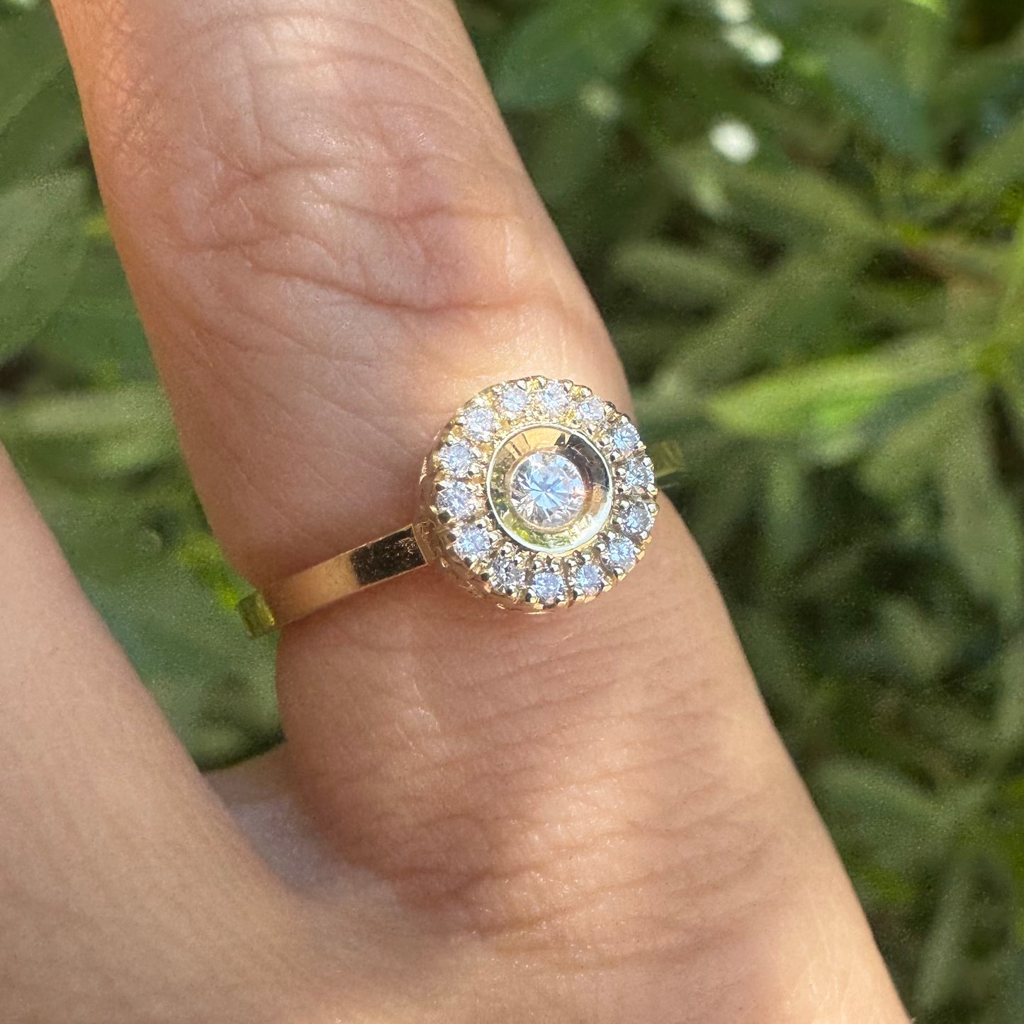 14K gold ring set with a bezel-set central Diamond, surrounded by a sparkling halo of brilliant-cut Diamonds.