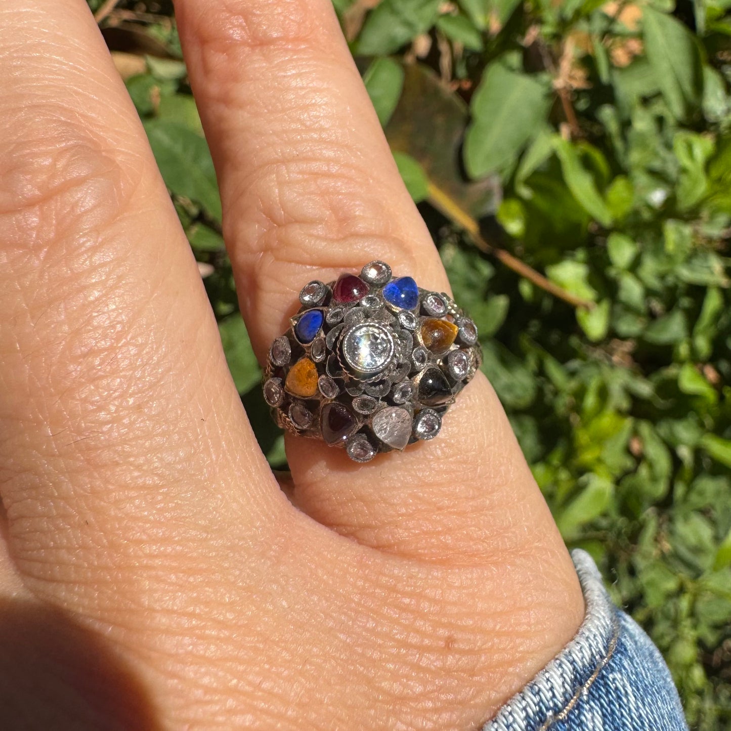 14K gold ring set with a central transparent gemstone surrounded by a vibrant mosaic of colorful gemstones -set in an ornate, handcrafted design