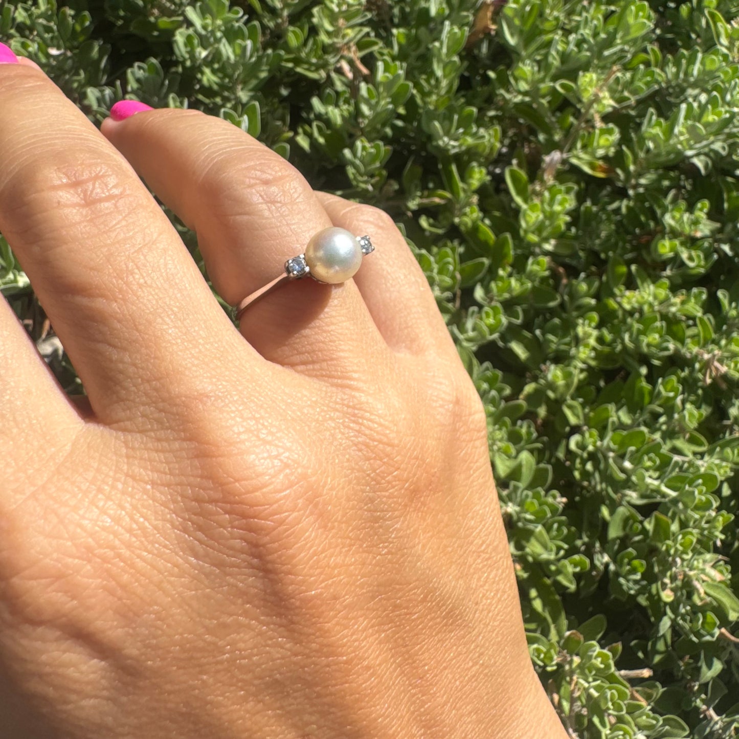 18K gold ring featuring a round Pearl at the center, flanked by two Diamonds.