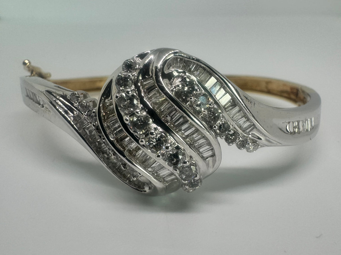 צמיד מרהיב מזהב לבן 14 קראט, בעיצוב גלים דינמי המשובץ בשיבוץ מרוכב של יהלומים עגולים ובחיתוך באגט.