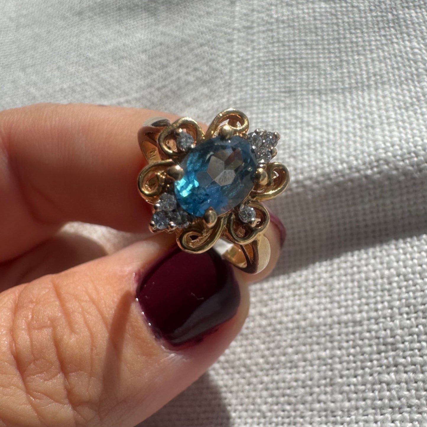 18K gold ring featuring an oval-cut Blue Topaz at the center, accented by sparkling side Diamonds and elegant scroll details.