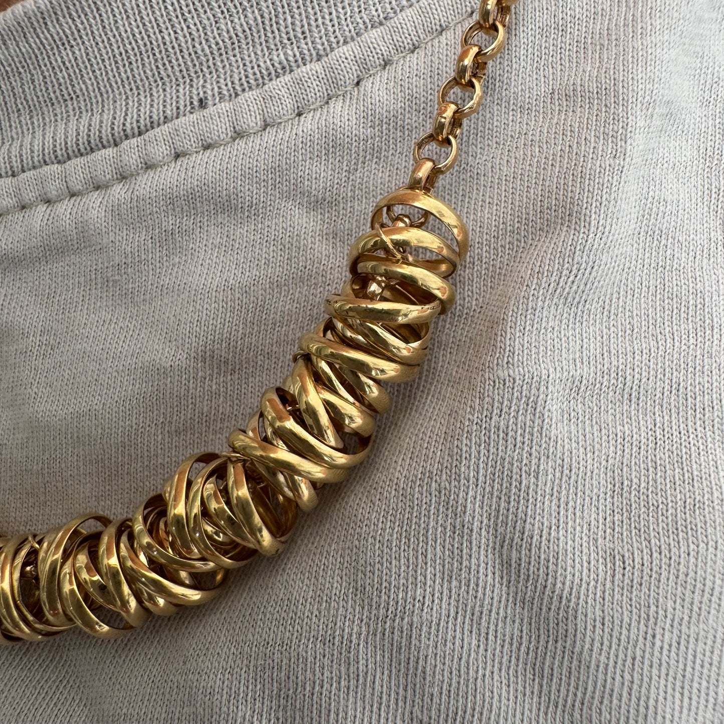 14K gold necklace featuring a series of intertwined gold rings creating a bold and sculptural design.