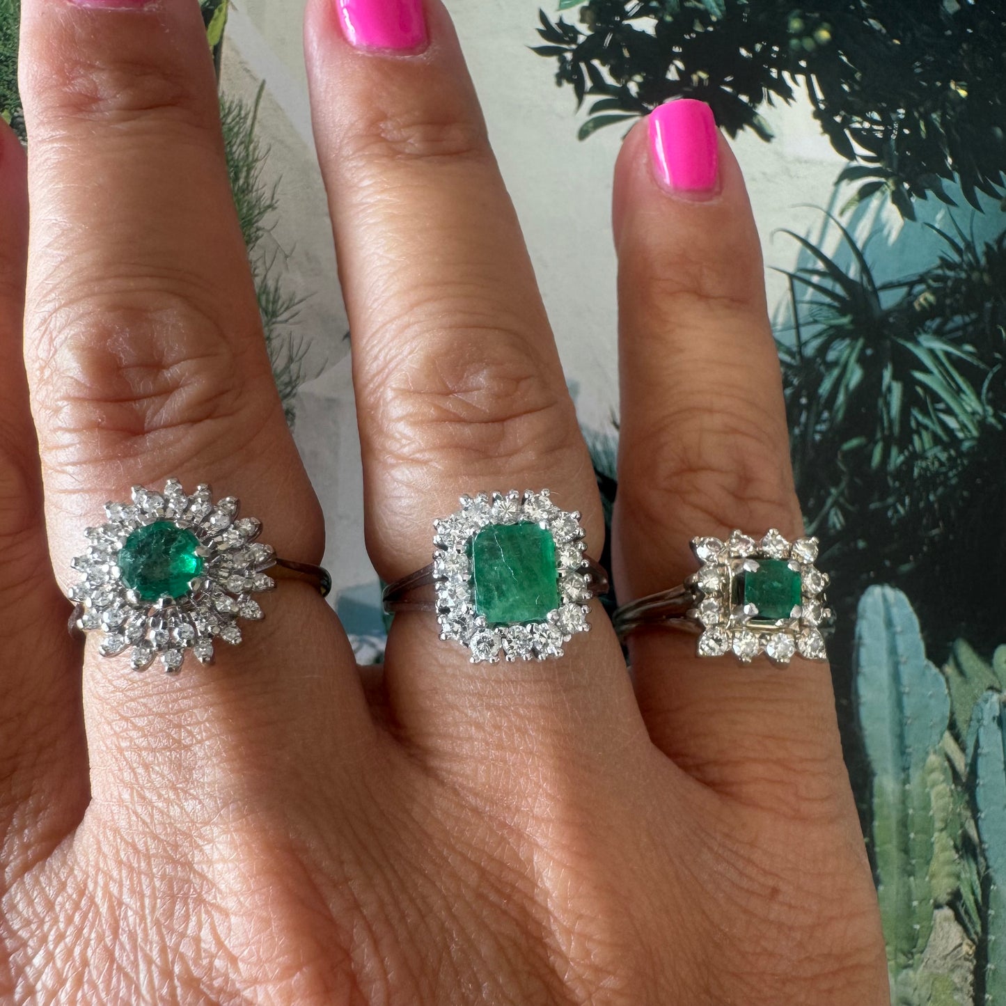 טבעת זהב לבן 18 קראט משובצת אבן אמרלד מרובעת במרכז, מוקפת בהילה נוצצת של יהלומים.