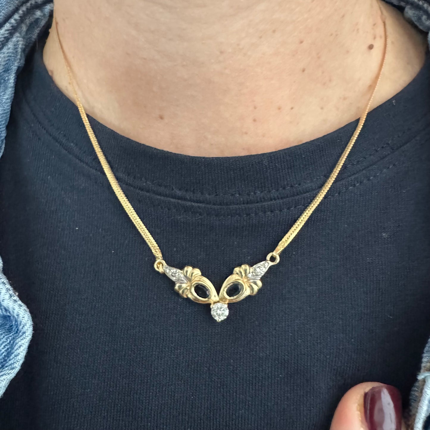 שרשרת זהב 14 קראט משובצת אבני ספיר כהות ויהלום מרכזי בחיתוך עגול.