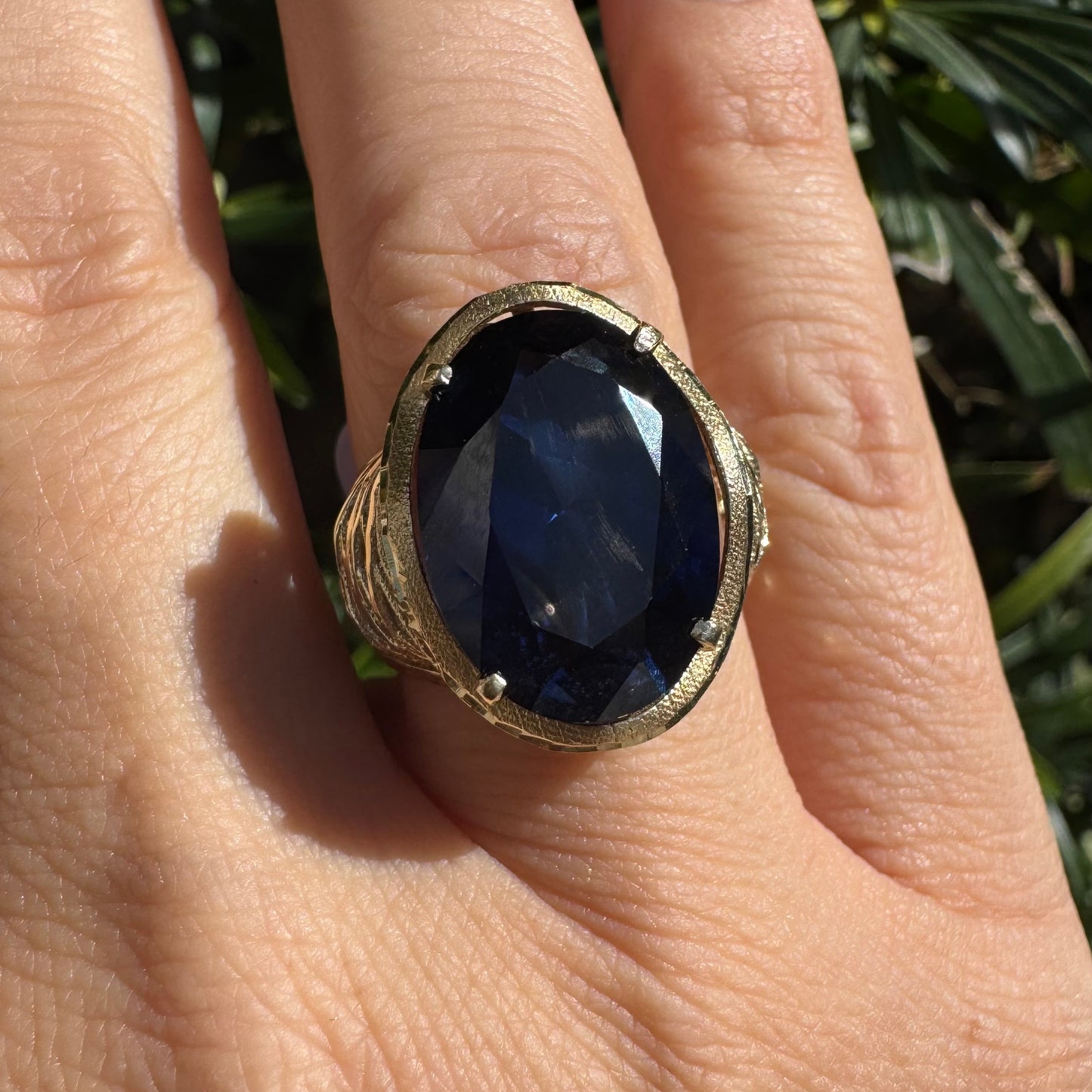 14K gold ring set with a deep navy-blue oval Sapphire in a dramatic openwork setting