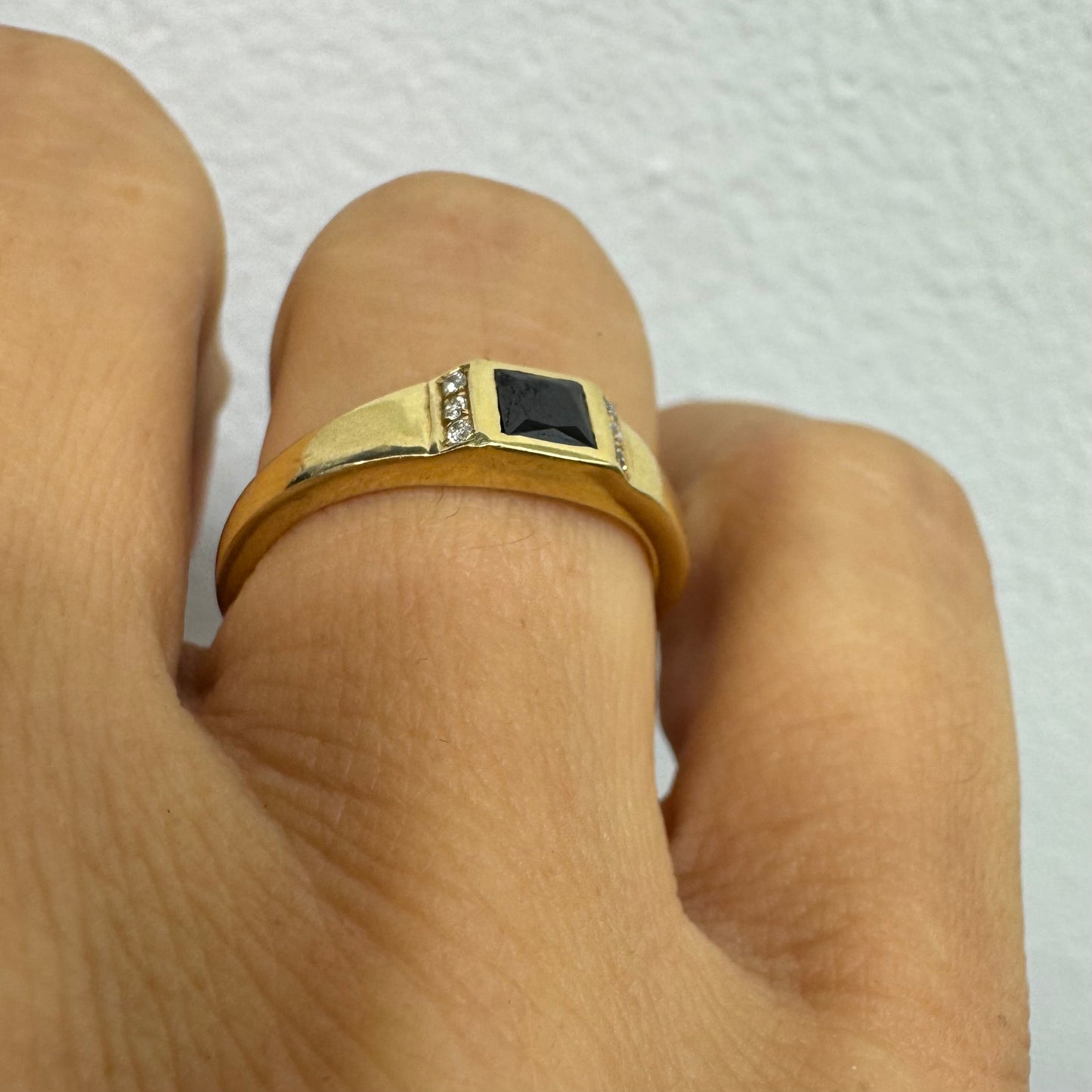 טבעת זהב 14 קראט משובצת אבן ספינל שחור בחיתוך ריבועי במרכז ויהלומים קטנים משני הצדדים.