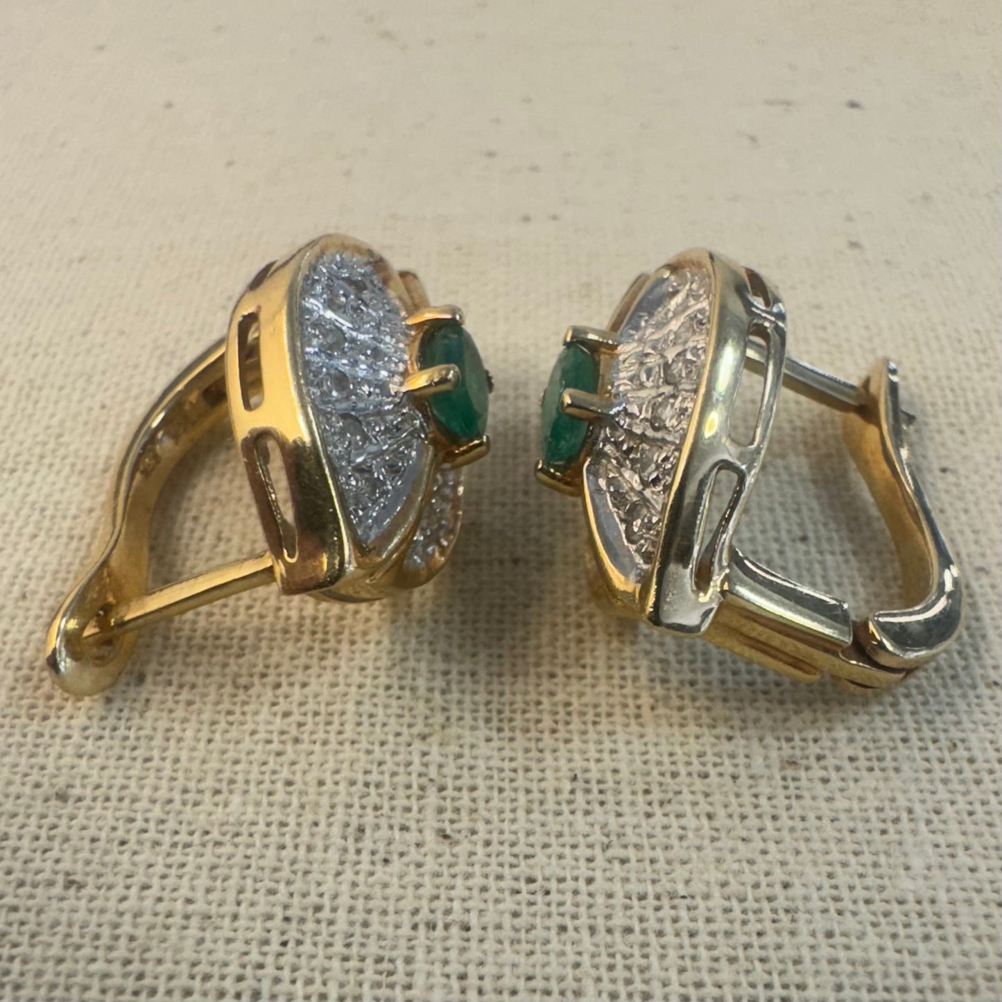 עגילים צמודים לאוזן, זהב צהוב 14 קראט, משובצים אמרלד במרכז, וסביבן פיתוחים משובצים יהלומים, שמעניקים מראה של ניצוץ רך ואלגנטי