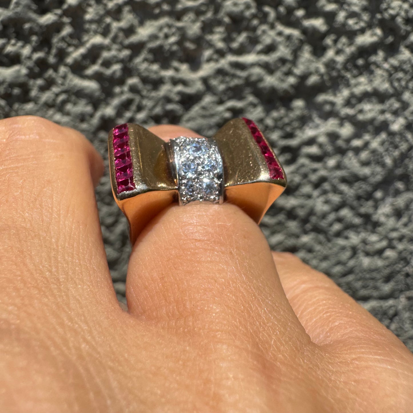 18K gold bow-shaped ring set with pavé Diamonds at the center and rows of square-cut Rubies on the sides.