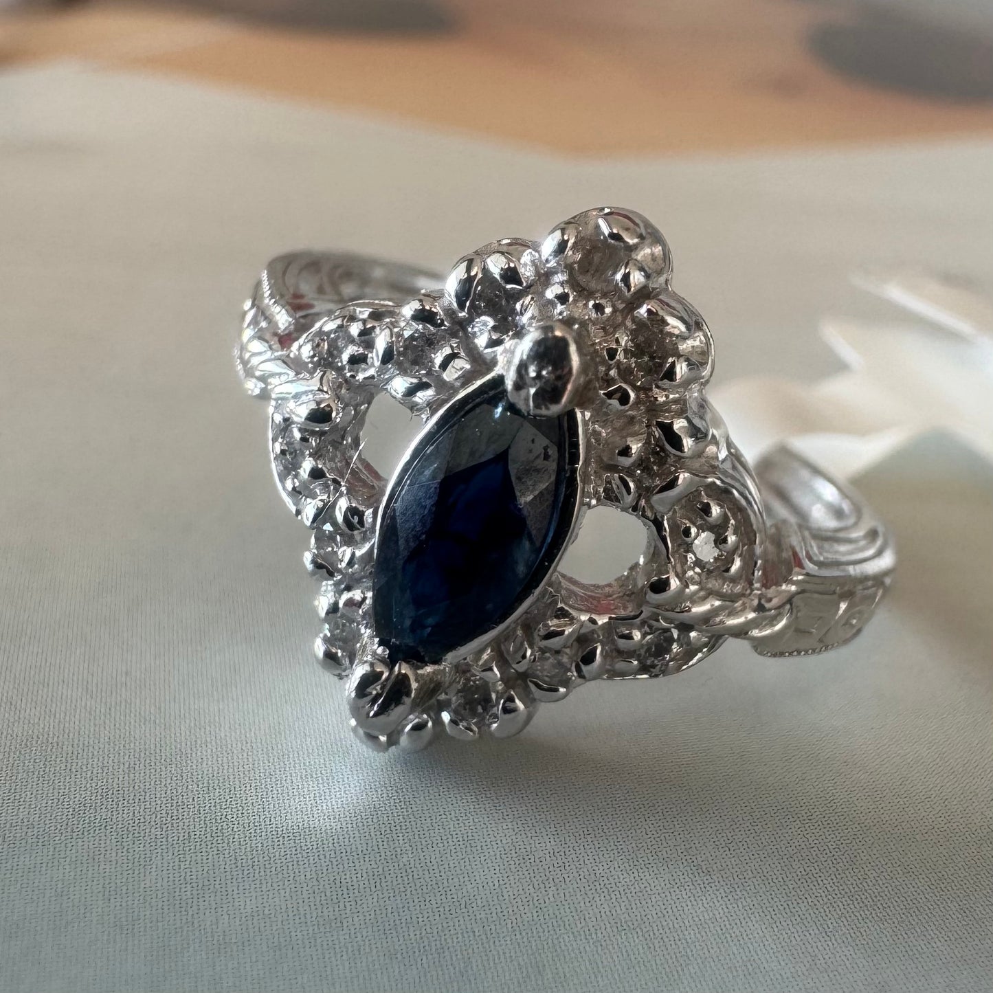 14K gold ring set with a marquise-cut Sapphire at its center, framed by an intricate halo of sparkling Diamonds