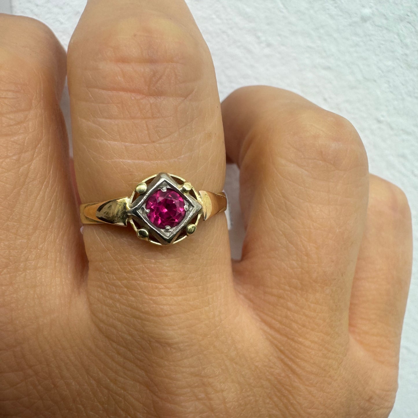 14K gold ring set with a vivid round-cut Ruby set in a geometric white gold frame.
