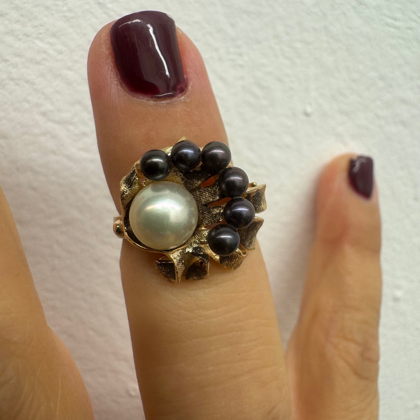 14K gold ring set with a luminous white Pearl at its center surrounded by a delicate circle of black Pearls.