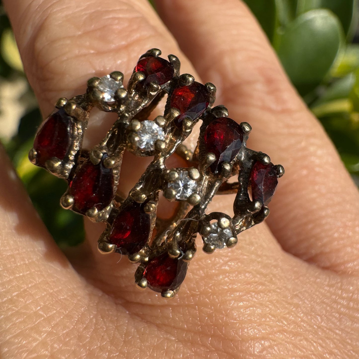 טבעת זהב צהוב 14 קראט משובצת אבני גרנט בחיתוך טיפה ויהלומים היוצרים יחד דוגמה גיאומטרית עזה ומלאת תנועה