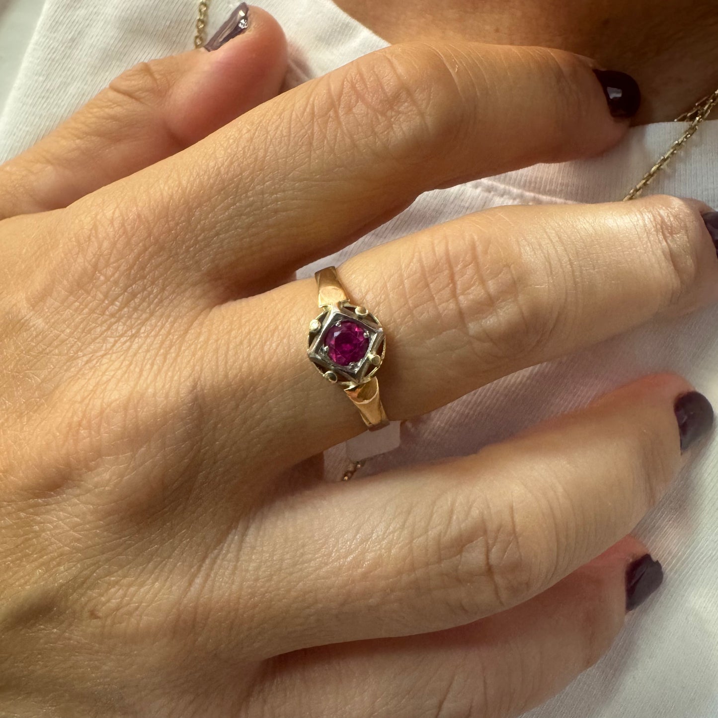 14K gold ring set with a vivid round-cut Ruby set in a geometric white gold frame.