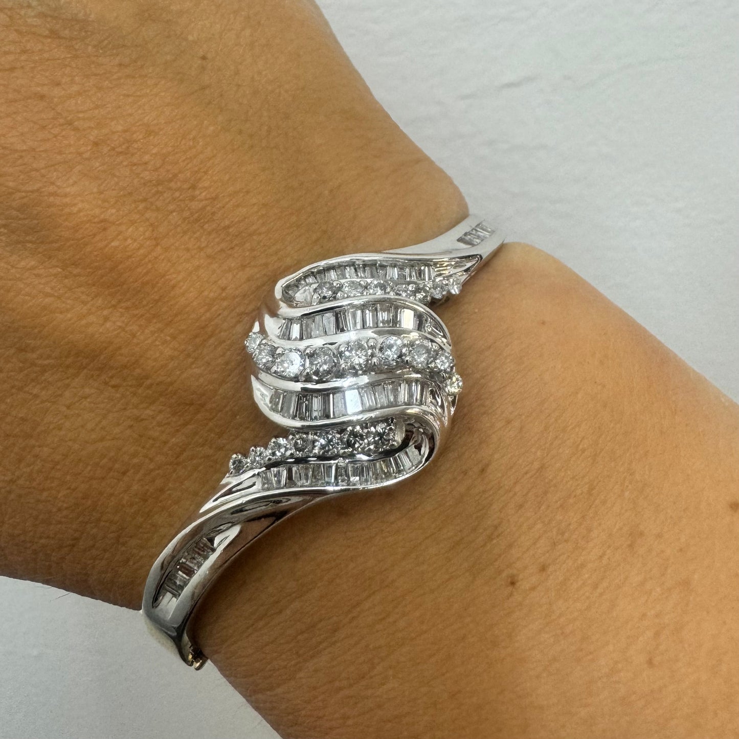 צמיד מרהיב מזהב לבן 14 קראט, בעיצוב גלים דינמי המשובץ בשיבוץ מרוכב של יהלומים עגולים ובחיתוך באגט.