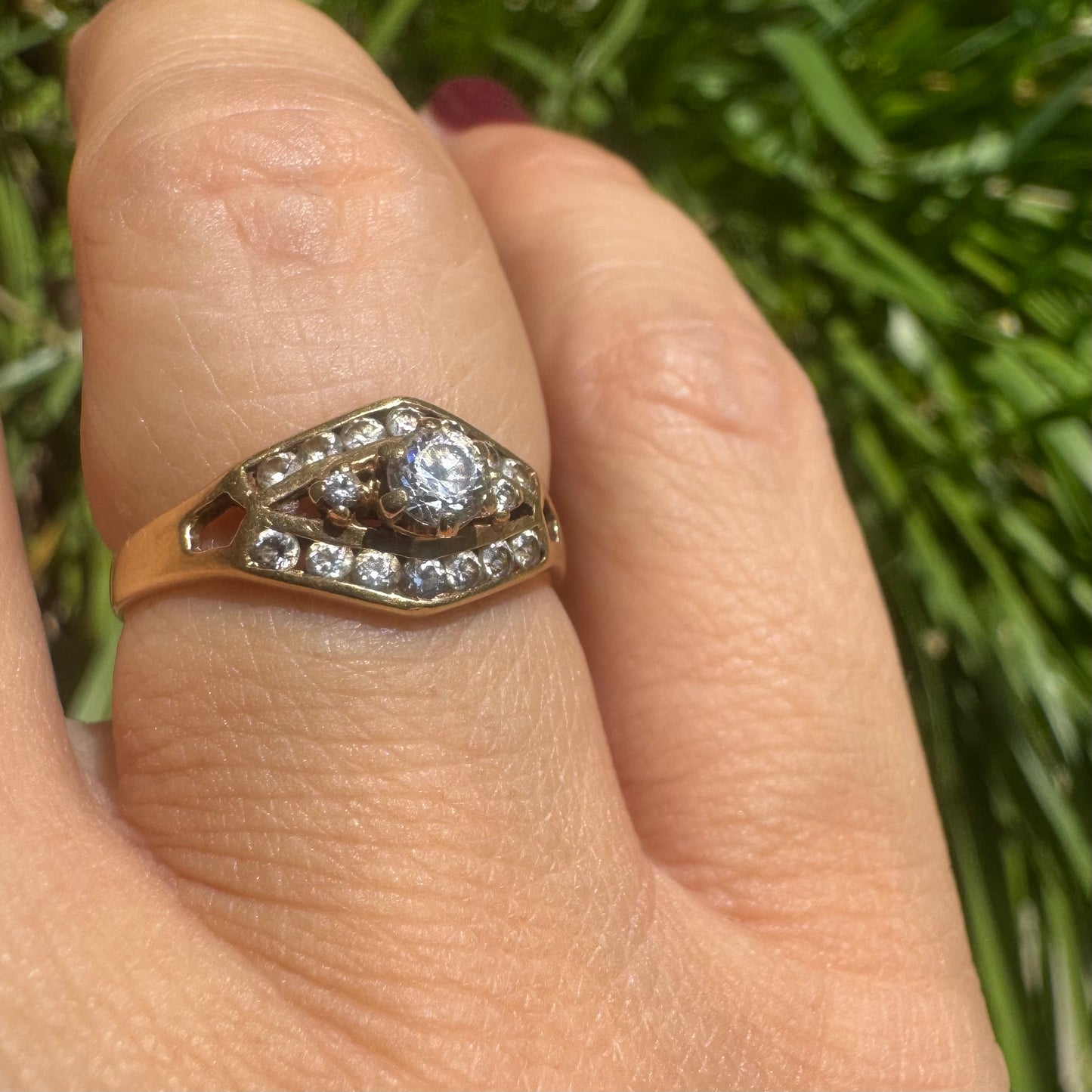 18K gold ring set with a central round Diamond, surrounded by rows of Diamonds in a decorative setting.