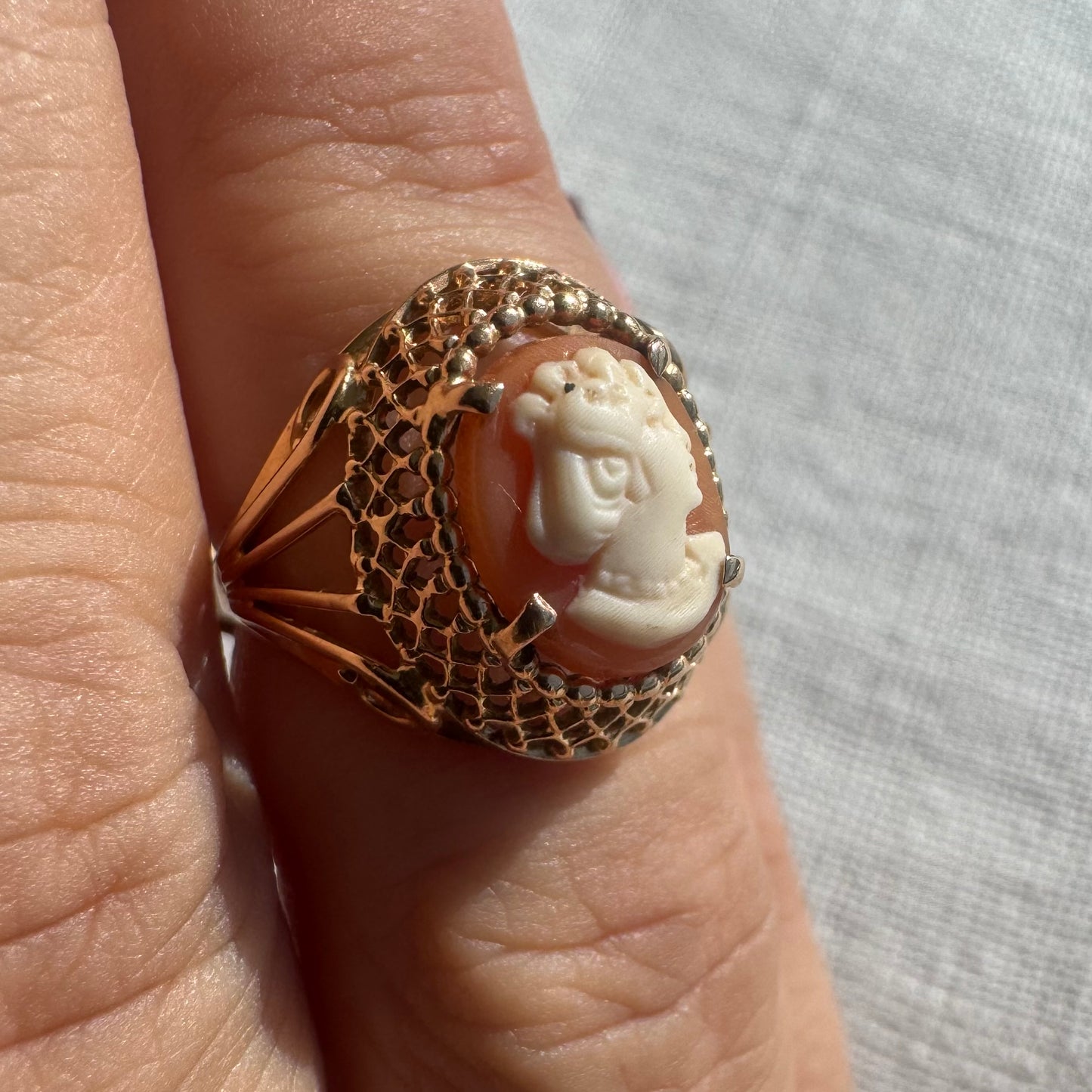 18K gold ring featuring a hand-carved Cameo of a delicate female profile in ivory tones on a warm Coral background.