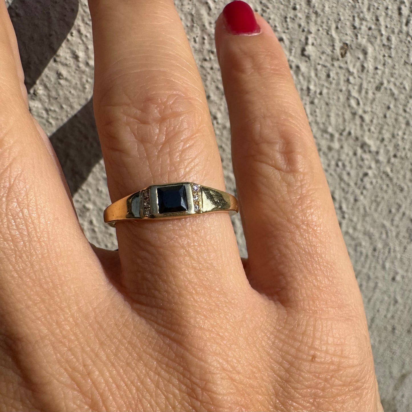 טבעת זהב 14 קראט משובצת אבן ספינל שחור בחיתוך ריבועי במרכז ויהלומים קטנים משני הצדדים.