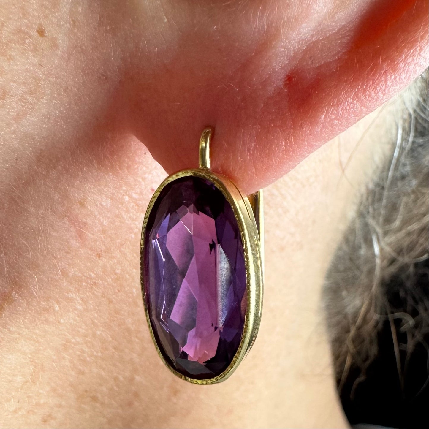 עגילי זהב צהוב 18 קראט, תלויים קצרים, משובצים באבני אמטיסט סגולות בחיתוך אובלי עמוק.