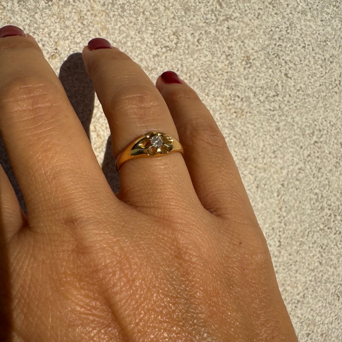 טבעת זהב צהוב 18 קראט בעיצוב פרח עדין, משובצת יהלום מרכזי בתוך עלי כותרת פתוחים.