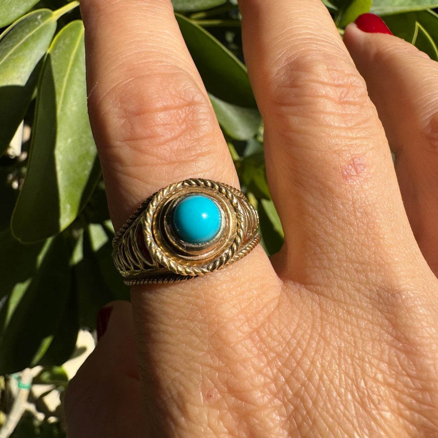 14K gold ring set with a round Turquoise stone at its center framed by a double rope-style bezel